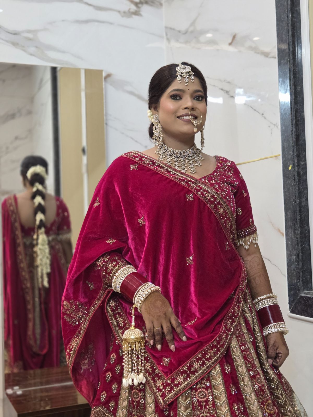 Nishtha after breast reduction - in deep red bridal lehenga with full jewellery set, standing in front of marble wall