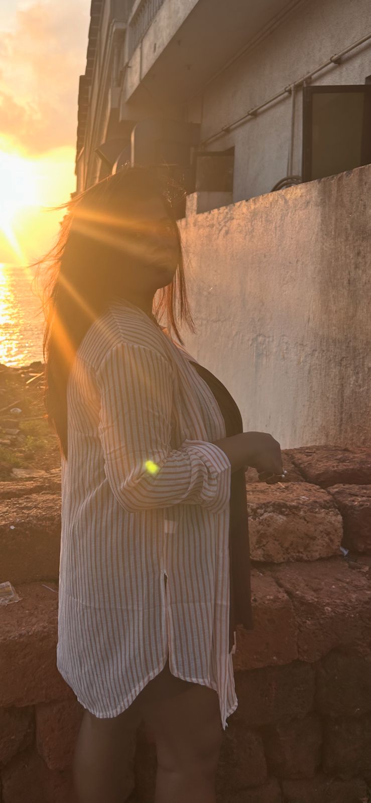 Nishtha before breast reduction - side profile in striped shirt at sunset, showing posture
